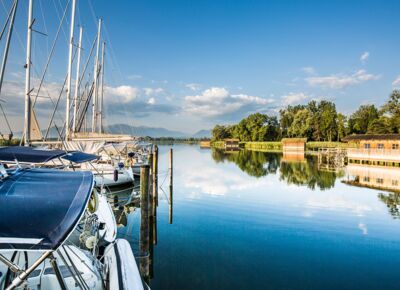 A harbour with sailing boats on a sunny day near the Gut Ising hotel on Lake Chiemsee.