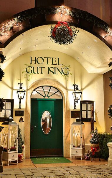 Entrance area of the Hotel Gut Ising at Chiemsee during Christmas time with big candles and lanterns in front of the entrance door.