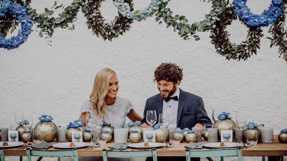 Brautpaar sitzt an der Hochzeitstafel, die in blauen Farben dekoriert ist.